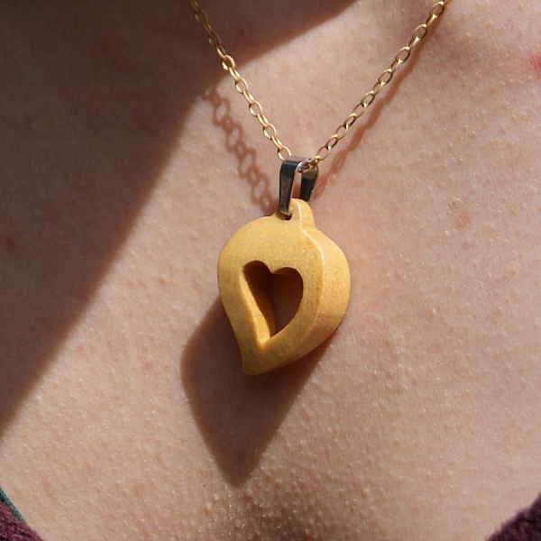 Pendentif en bois en forme de cœur sur chaîne dorée.